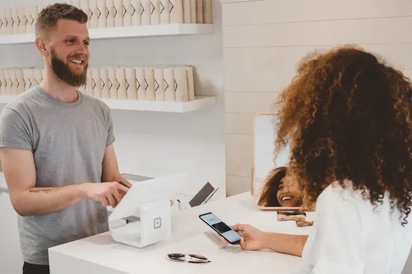 A smiling customer at the counter holding her phone, the happy moment to ask for a customer testimonial video